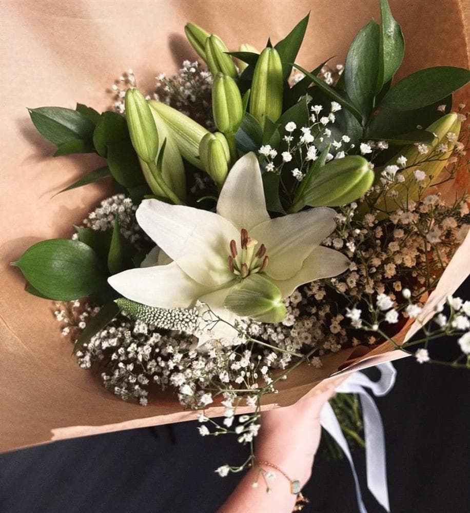A white lily bouquet wrapped in kraft paper