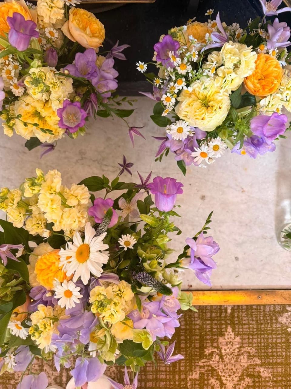 Pale yellow and lilac flowers gathered on the studio workbench