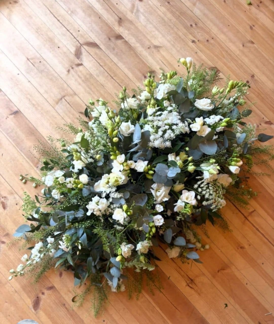 A white and green funeral spray made by Bramble & Petal