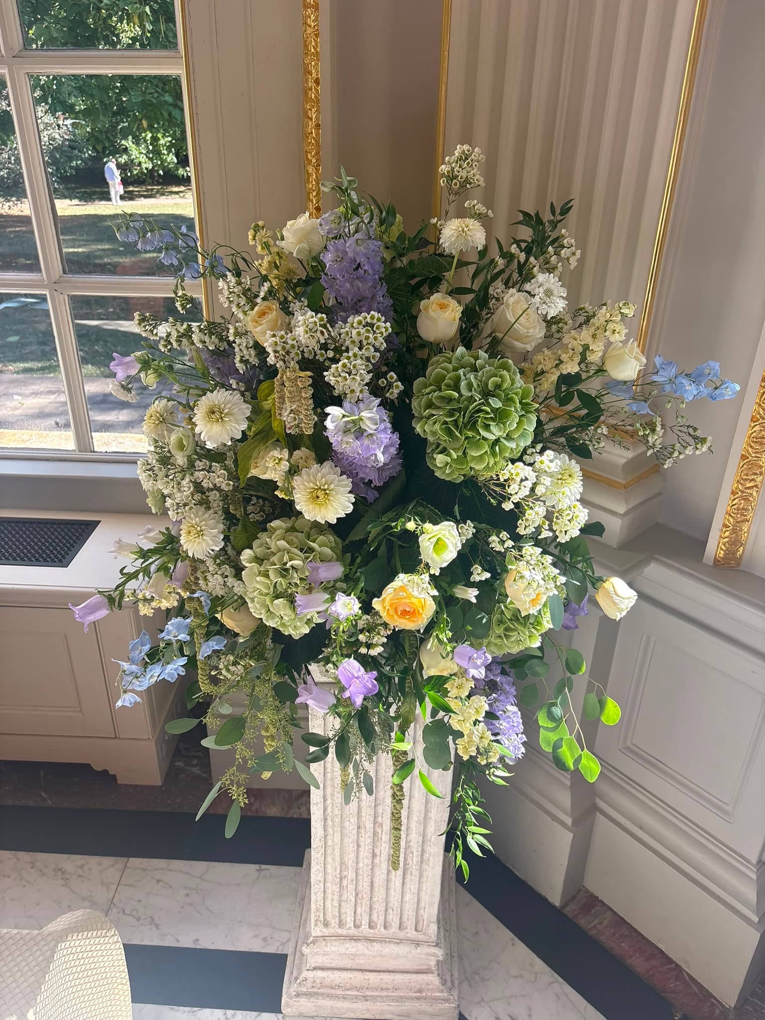 A wedding arrangement of green hydrangeas, pale yellow roses, white flowers and lilac stems