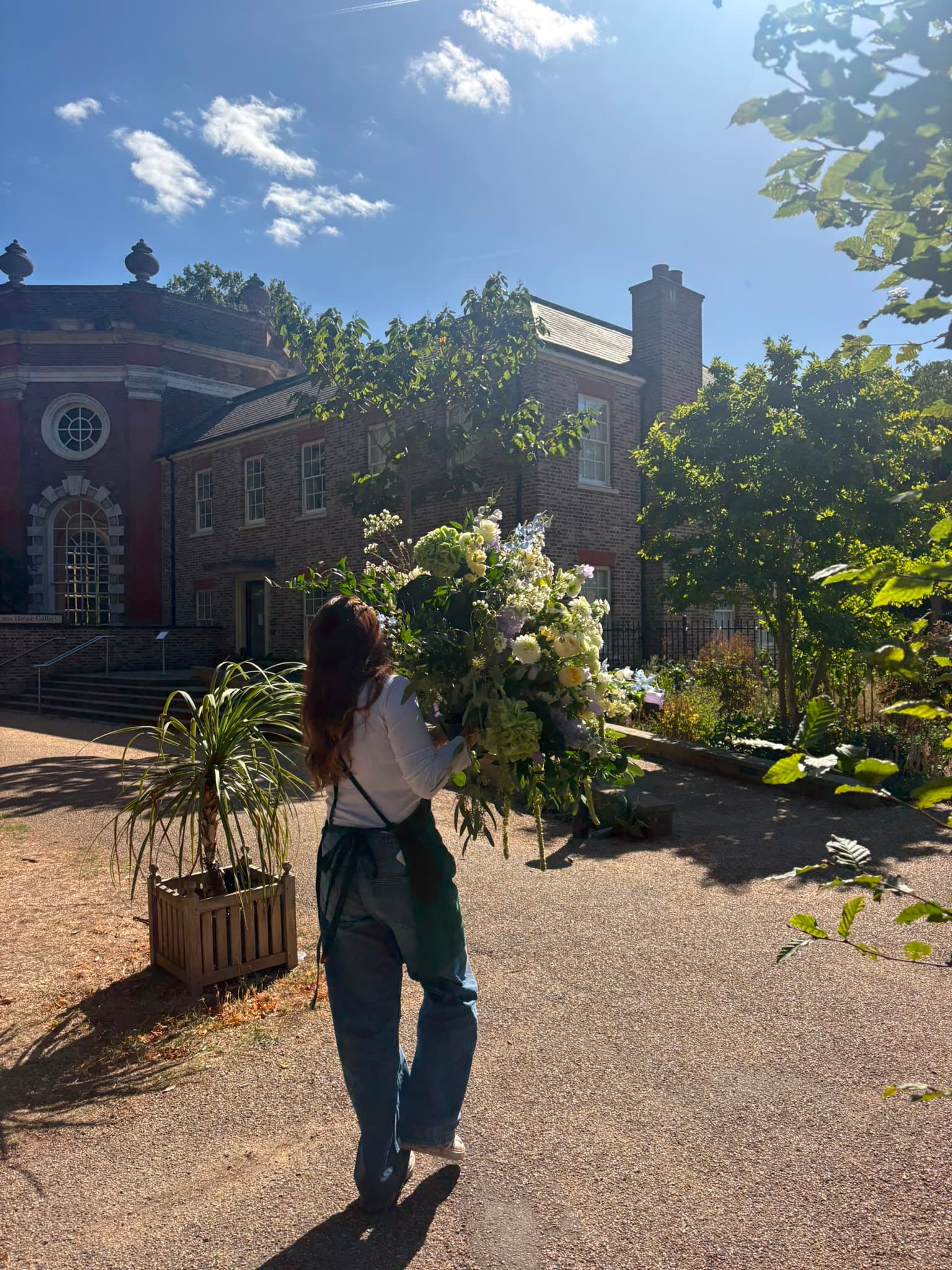 A florist carrying a large wedding flower arrangement towards the venue